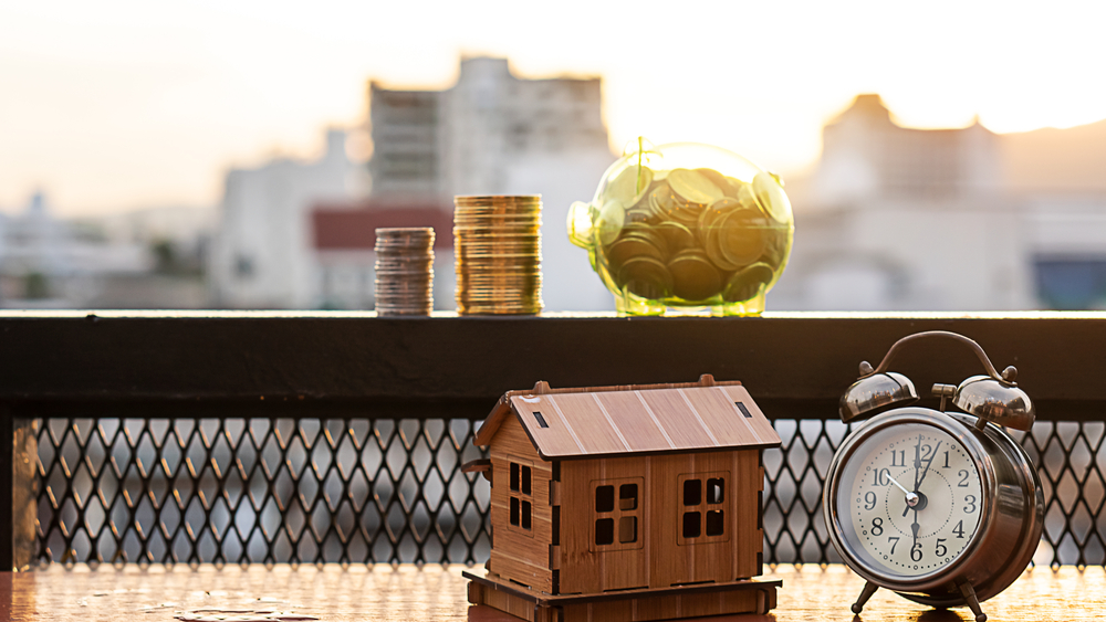 Small clock and house model representing property ownership, illustrating the process of buying property in Ghana for overseas buyers.